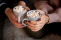 Happy couple`s hands holding hot cups with hot drinks with marshmallow Royalty Free Stock Photo