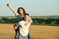 Happy couple having fun on outdoor, girl riding on man back and fly - romantic travel and people concept, summer landscape with Royalty Free Stock Photo