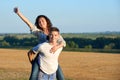 Happy couple having fun on outdoor, girl riding on man back and fly - romantic travel and people concept, summer landscape with Royalty Free Stock Photo