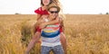 Happy Couple Having Fun Outdoors on wheat field. Laughing Joyful Family together. Freedom Concept. Piggyback Royalty Free Stock Photo