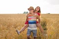 Happy Couple Having Fun Outdoors on wheat field over sunset. Laughing Joyful Family together. Freedom Concept. Piggyback Royalty Free Stock Photo