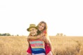 Happy Couple Having Fun Outdoors on wheat field over sunset. Laughing Joyful Family together. Freedom Concept. Piggyback Royalty Free Stock Photo