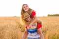 Happy Couple Having Fun Outdoors on wheat field over sunset. Laughing Joyful Family together. Freedom Concept. Piggyback Royalty Free Stock Photo