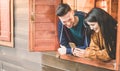 Happy couple having fun with smartphone inside camping wood house - Young people enjoying mountain vacation - Love, travel and