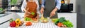 Happy couple having fun standing in kitchen at home preparing vegetable salad husband and wife vegetarians chop vegetables prepare