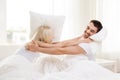 Happy couple having pillow fight in bed at home Royalty Free Stock Photo