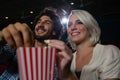 Couple having popcorn while watching movie in theatre