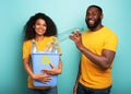 Happy couple hold a plastic container with bottles over a light blue color. Concept of ecology, conservation, recycling