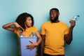 Happy couple hold a plastic container with bottles over a light blue color. Concept of ecology, conservation, recycling Royalty Free Stock Photo