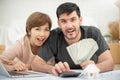Happy couple holding money and calculating their budget. Royalty Free Stock Photo