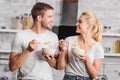 happy couple holding plates and spoons with corn flakes and looking at each other Royalty Free Stock Photo