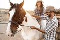Happy couple with horse having fun at farm ranch - Focus on man face Royalty Free Stock Photo