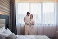 Happy couple in hotel room in the morning. Just married man and woman standing at window