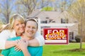 Happy Couple Hug In Front of Sold Real Estate Sign and New House Royalty Free Stock Photo