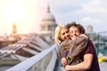 Happy couple hugging by Millennium bridge, River Thames, London.