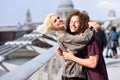 Happy couple hugging by Millennium bridge, River Thames, London.