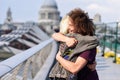 Happy couple hugging by Millennium bridge, River Thames, London.