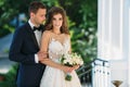 Happy couple hugging and smiling in garden with green trees. The bride in a black suit with a bow tie and a bride in a Royalty Free Stock Photo