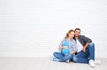 Happy couple husband and pregnant wife near blank brick wall