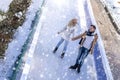 Happy couple ice skating and enjoying the snowfall at the ice rink in the park in winter Royalty Free Stock Photo