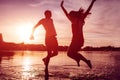 Happy couple jumping on summer river bank. Young man and woman having fun at sunset. Guys hanging together Royalty Free Stock Photo