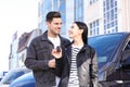 Happy couple with key near car on street. Buying new auto Royalty Free Stock Photo