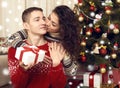 Happy couple kiss in christmas decoration at home. New year eve, ornated fir tree. Winter holiday and love concept. Royalty Free Stock Photo