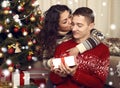 Happy couple kiss in christmas decoration at home. New year eve, ornated fir tree. Winter holiday and love concept. Royalty Free Stock Photo