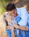 Happy couple, kiss and hug in nature for affection, love or support in outdoor walk or bonding. Young woman kissing man Royalty Free Stock Photo