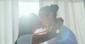 Happy, couple kiss and love in home lens flare, bonding and romance together in the morning. Intimate, interracial and