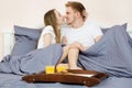 Happy couple kissing in bed with orange juice in the morning : Romantic couple drinking orange juice lying on their bed Royalty Free Stock Photo