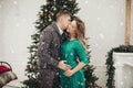 Happy couple kissing feeling love at Christmas tree luxury interior decoration