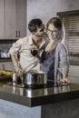 Happy couple kissing and flirting while cooking a meal in the kitchen Royalty Free Stock Photo