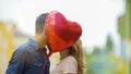 Happy couple kissing, hiding behind heart balloon, romantic relationship, date Royalty Free Stock Photo