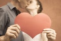 Happy couple kissing and holding heart at red wall background Royalty Free Stock Photo