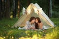 Happy couple is kissing in the tent at summer evening