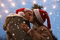 Happy couple kissing under mistletoe bunch outdoors in snowy evening, low angle view