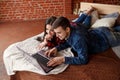 Happy couple with laptop shopping online at home, browsing internet in bed, smiling and having fun Royalty Free Stock Photo