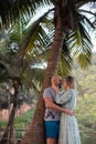 Happy couple look at each other and embrace under palm tree while relaxing in tropical paradise. Love and happiness. Royalty Free Stock Photo