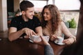 Happy couple in cafe look into smartphone and smile. Woman show to man and woman something in phone. Man put finger on Royalty Free Stock Photo