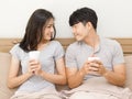 Happy couple in love. asian young man and woman holding coffee cup on the bed. The lover smile and look at each other face happily Royalty Free Stock Photo