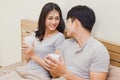 Happy couple in love. asian young man and woman holding coffee cup on the bed. The lover smile and look at each other face happily Royalty Free Stock Photo