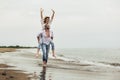 Couple in love on beach summer vacations. Joyful girl piggybacking on young boyfriend having fun