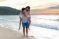 Happy couple in love on beach summer vacations. Joyful girl piggybacking on young boyfriend having fun