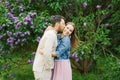 Happy couple in love in blooming lilac gardens in spring. The guy kisses the girl on the cheek, who smiles