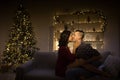 Happy, couple in love in the dark, evening on the couch, dark background, christmas tree lights. Christmas evening. New Year. hug Royalty Free Stock Photo
