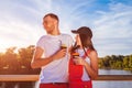 Happy couple in love having coffee, hugging and laughing on the bridge at sunset Royalty Free Stock Photo