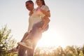 Couple having fun in spring forest. Man rides his girlfriend on back at sunset. Royalty Free Stock Photo