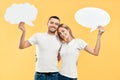Happy couple in love holding paper thought bubbles over yellow background