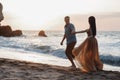 Happy couple in love during honeymoon on a rocky beach near the blue ocean